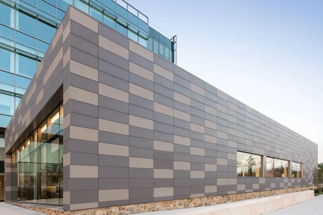 Grey metal rainscreen panels along a long angular commercial facade — aluminium composite (ACM) panel cladding system