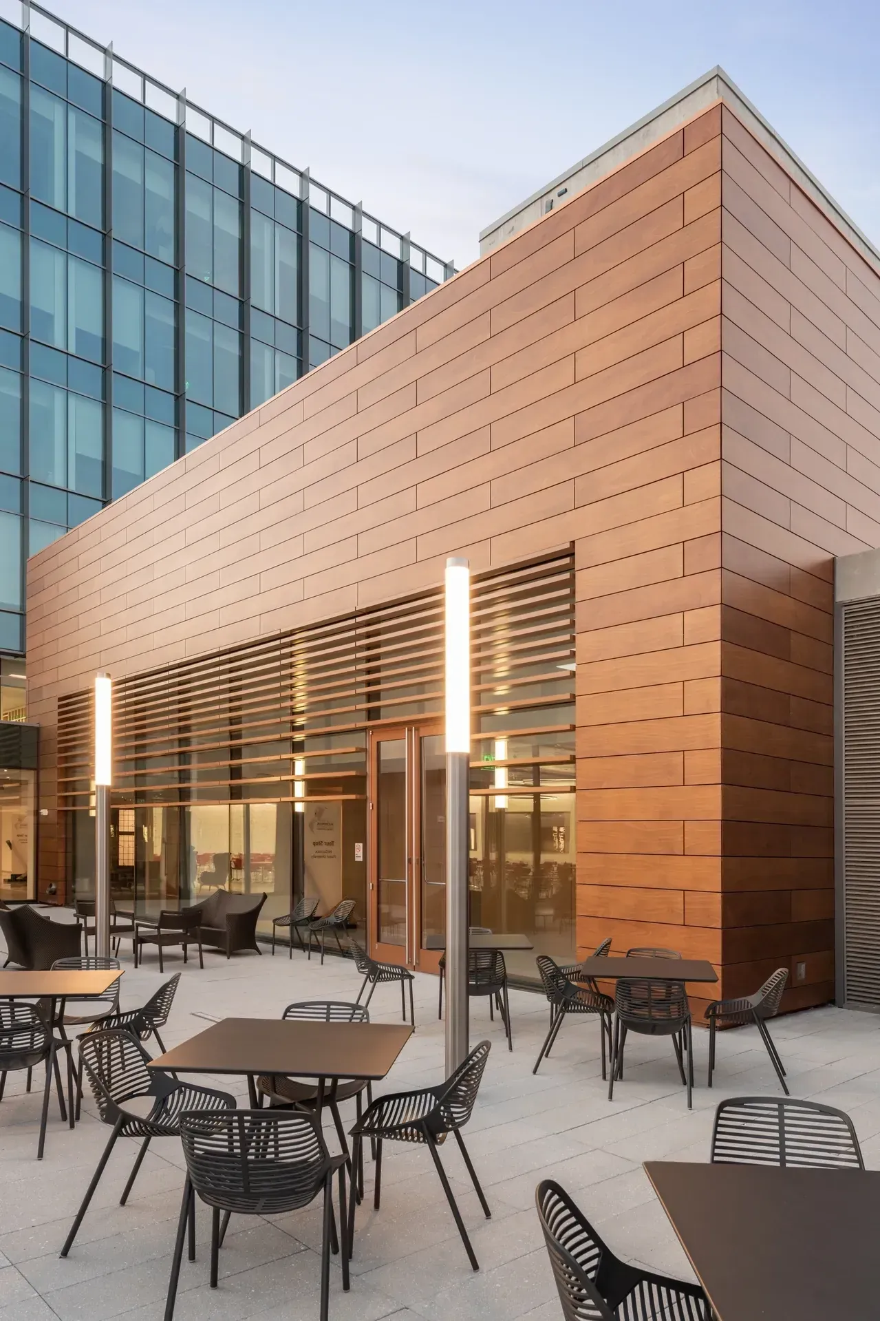Terracotta rainscreen cladding panels wrapping a commercial building corner beside a glass curtain wall