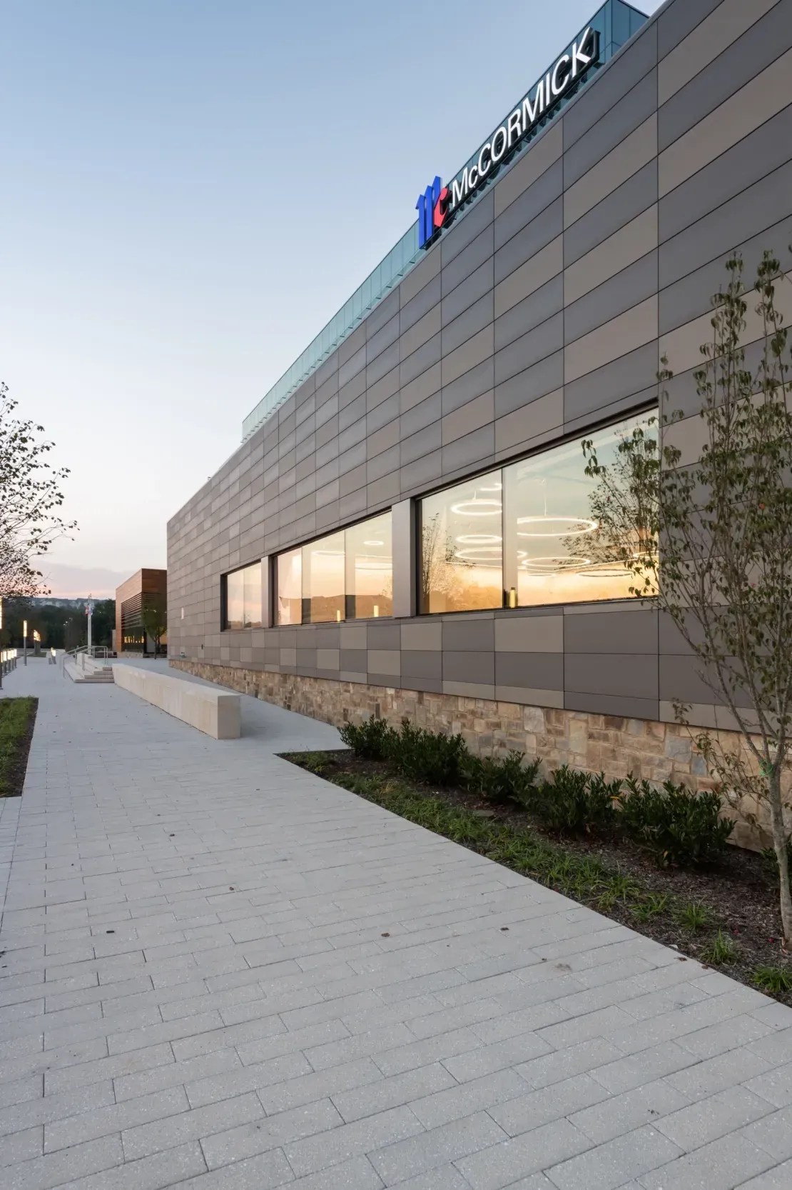 Pale ultra-high-performance concrete (UHPC) rainscreen panels on a commercial facade lit at dusk